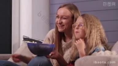 微笑迷人的妈妈和她可爱的女儿戴着眼镜坐在客厅舒适的沙发上看喜剧